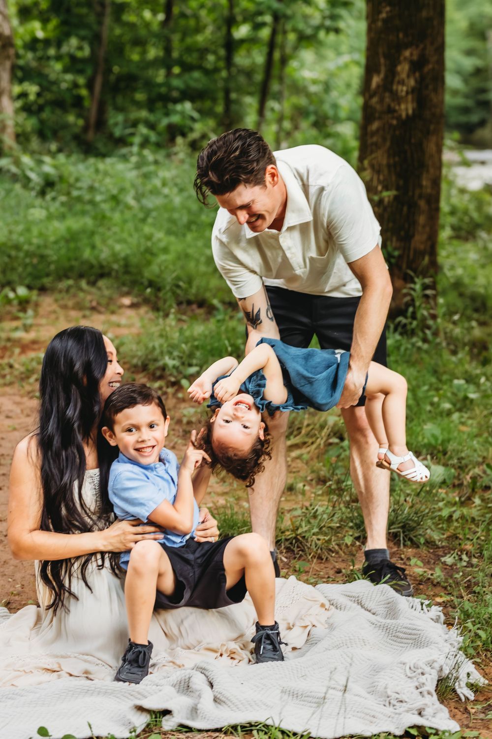 Family plays and laughs together on blanket during casual outdoor photo session in Hamden, CT.