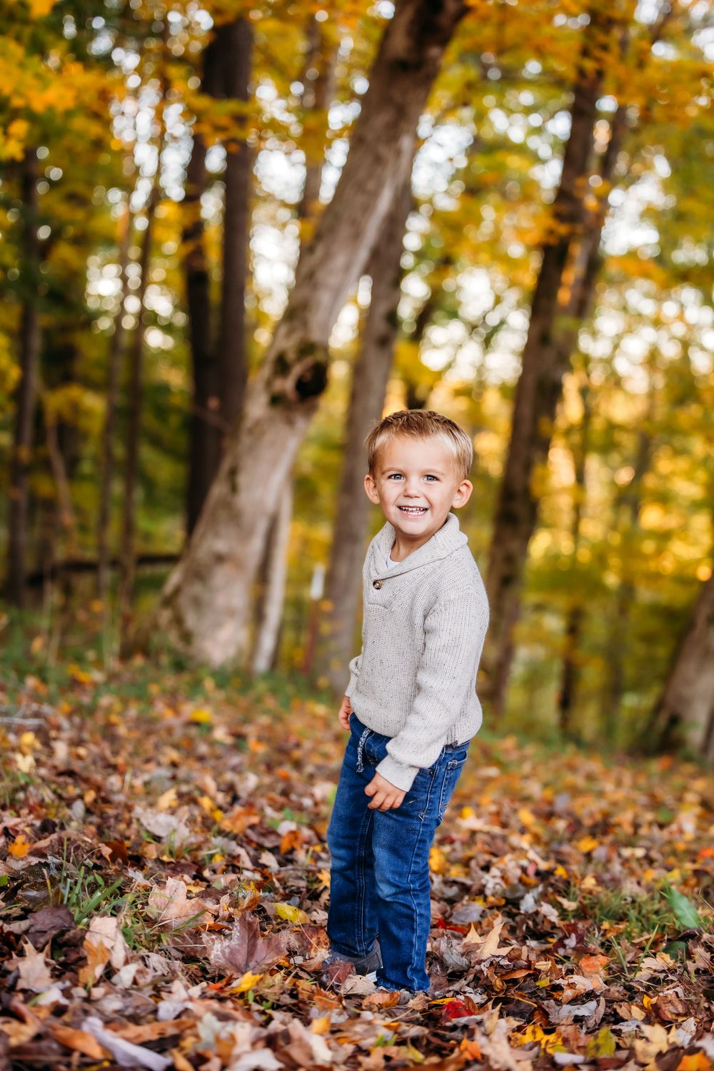 A young boy smiles at sunset in a forest during a photo session in Woodbury, CT