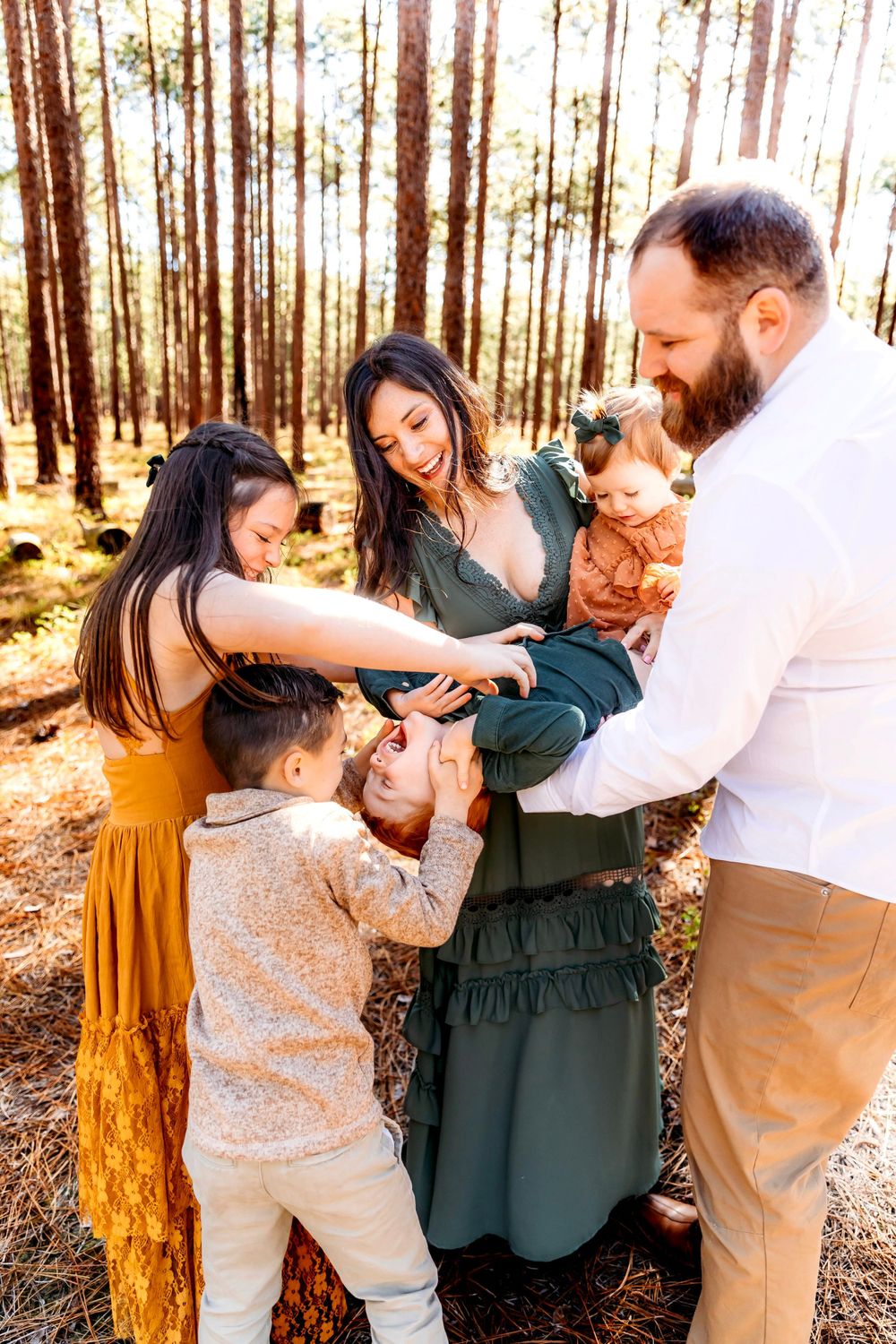 A family shares a tender moment together in North Haven, CT at a sunlit forest setting.