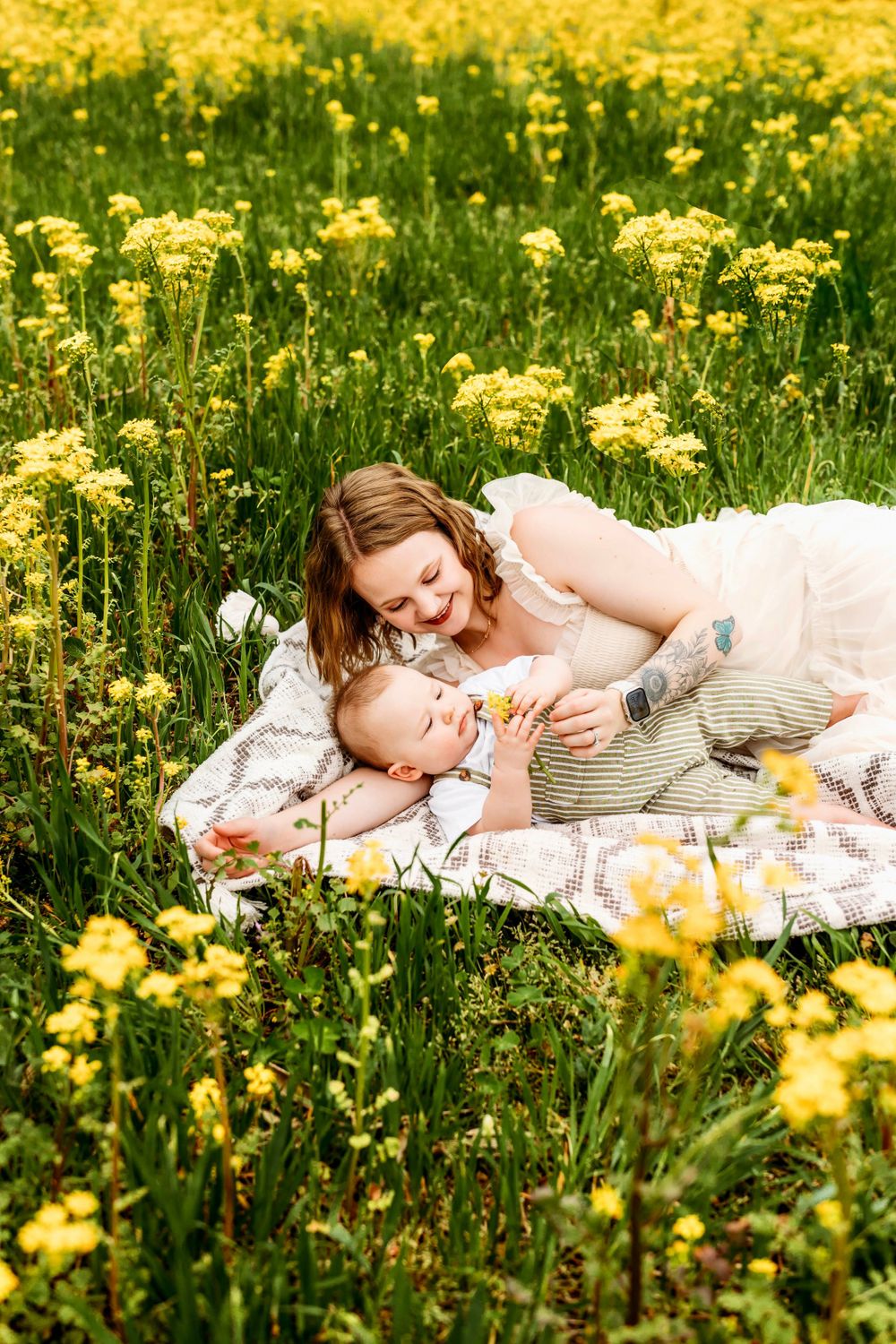 Mother and baby lying on blanket surrounded by blooming yellow wildflowers in Waterbury, CT.