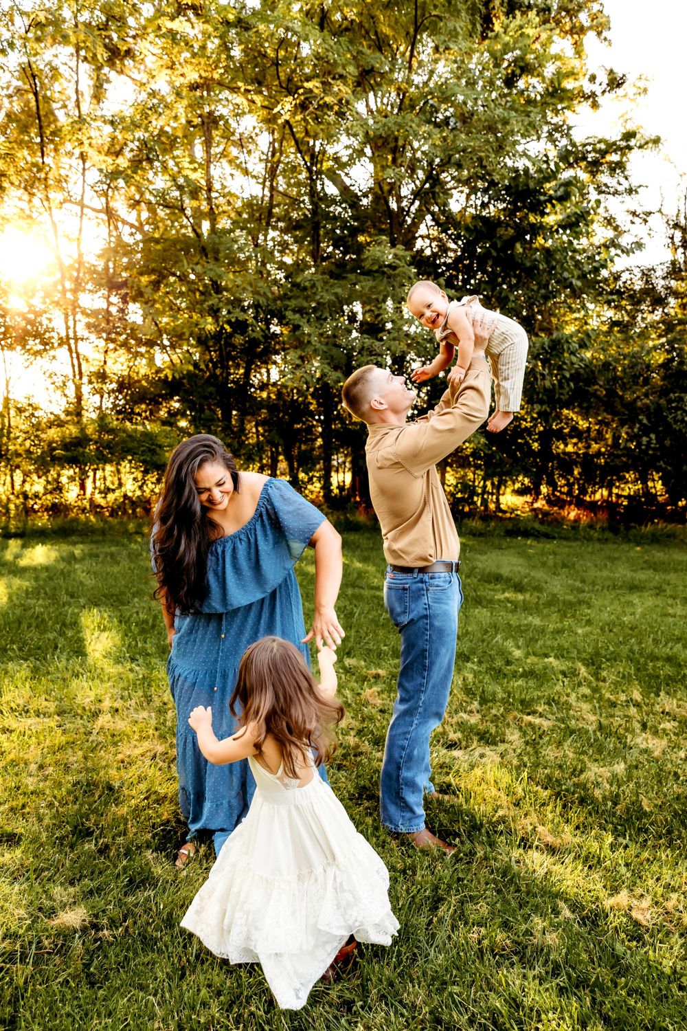 Playful family moments captured in golden sunlight as they lift and spin in grassy field Branford, CT.