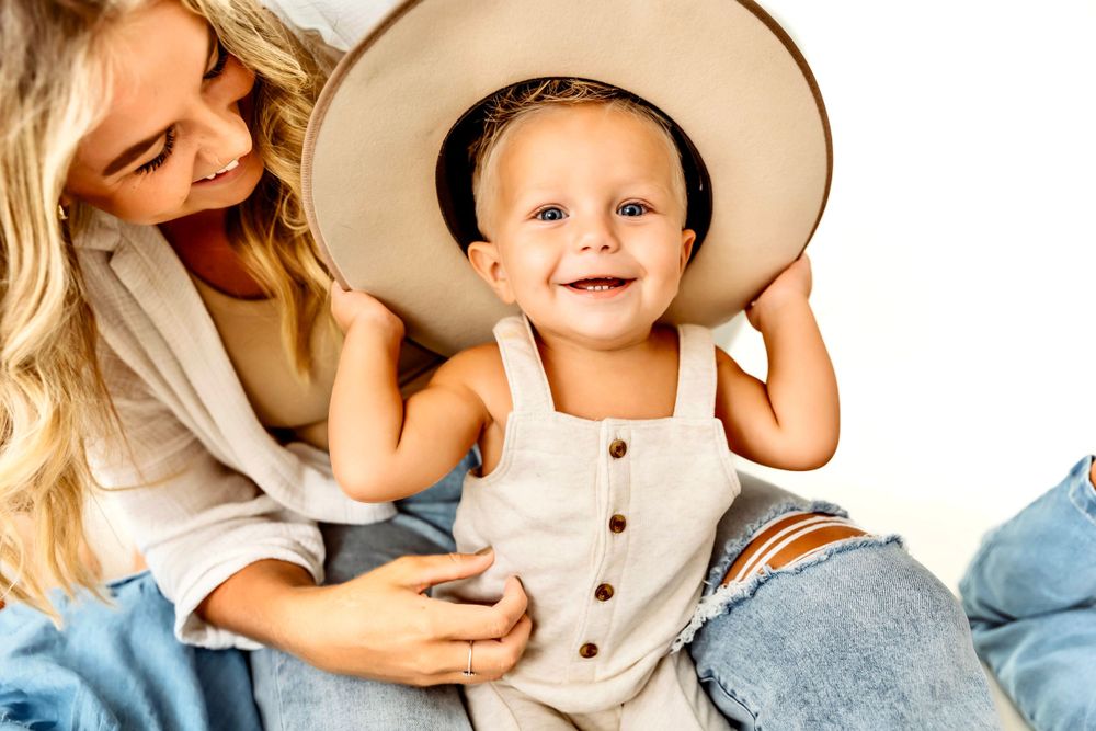 Family wearing neutral colors and straw hats poses for playful lifestyle portraits in Hamden, CT.