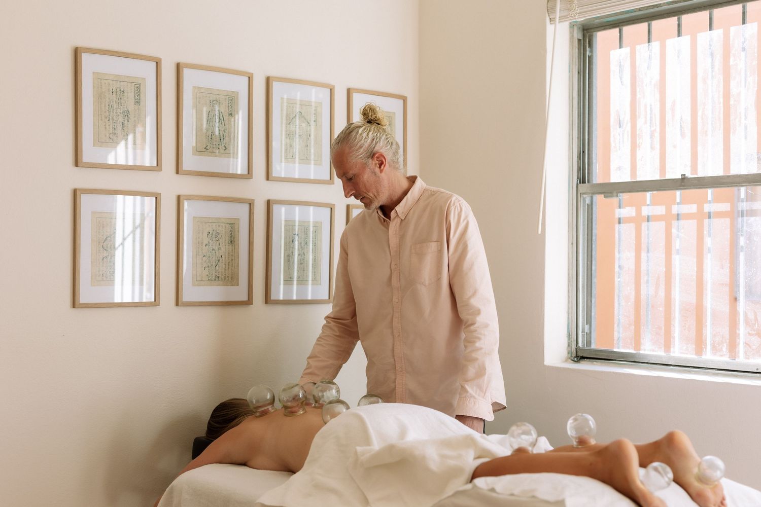 Therapist performing cupping therapy on a client lying on a massage table in a serene spa room.