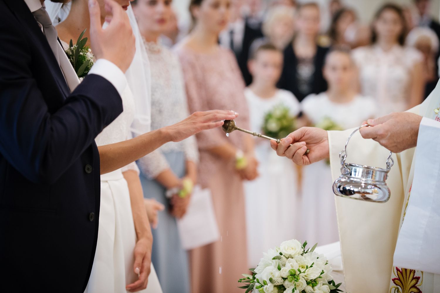 Black and white wedding photo of couple receiving blessing with incense during ceremony.