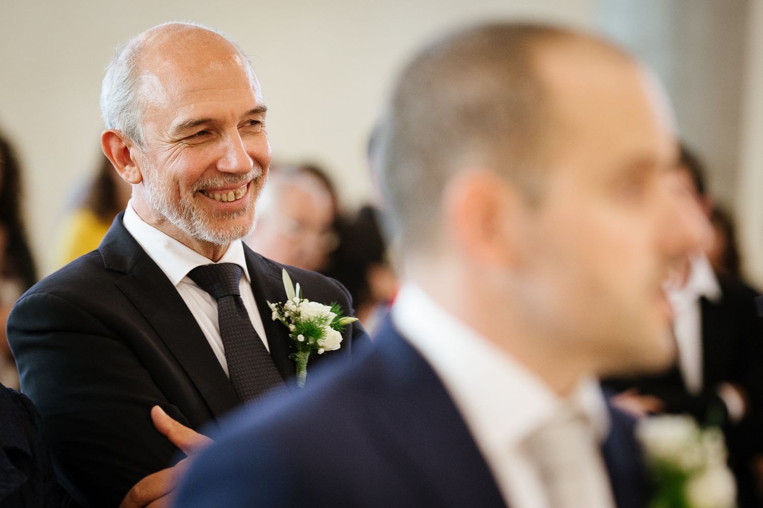 Black and white wedding photo of smiling guest watching ceremony in church.