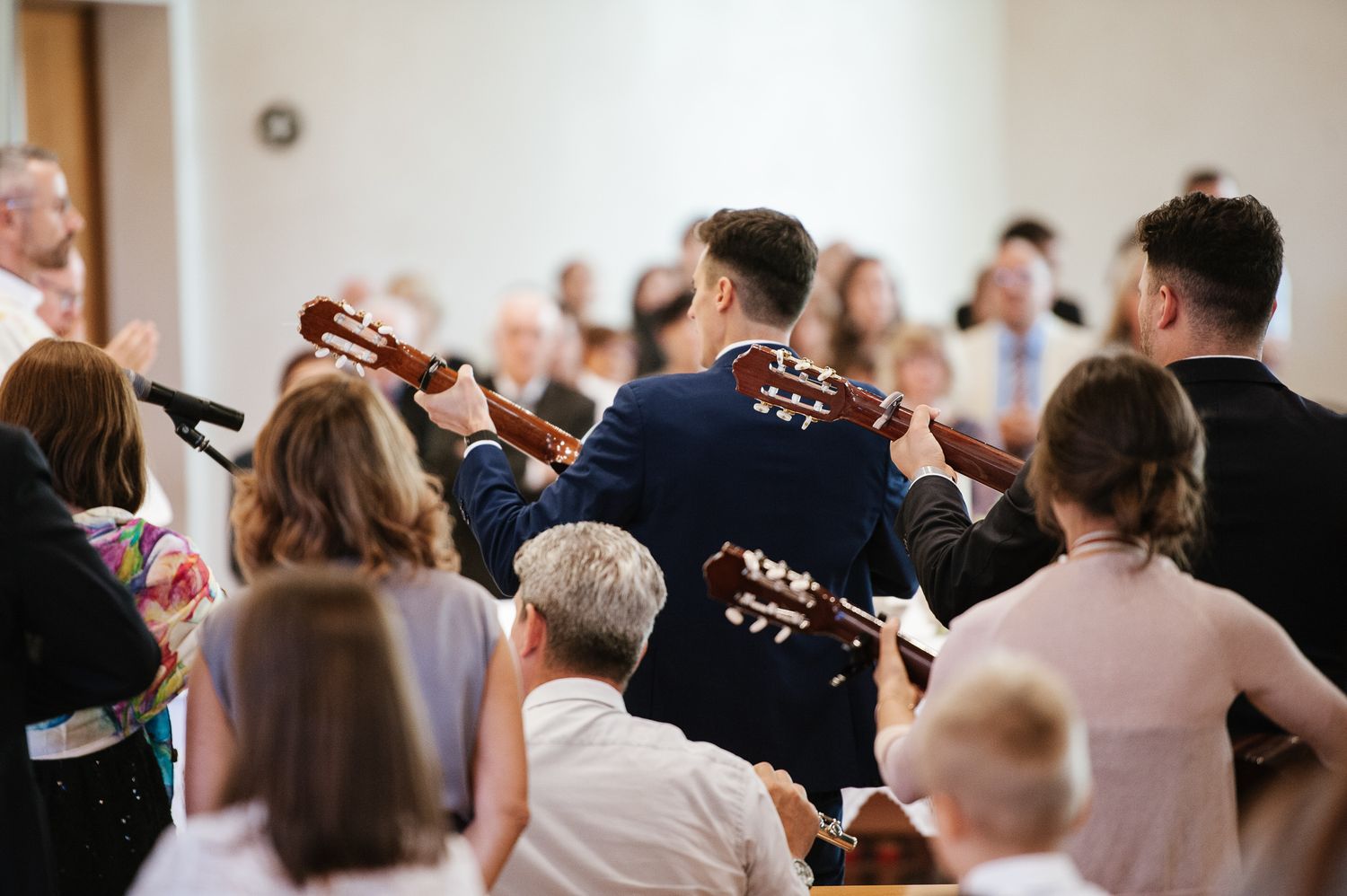 Musicians playing acoustic guitars for wedding guests during an outdoor wedding reception celebration.