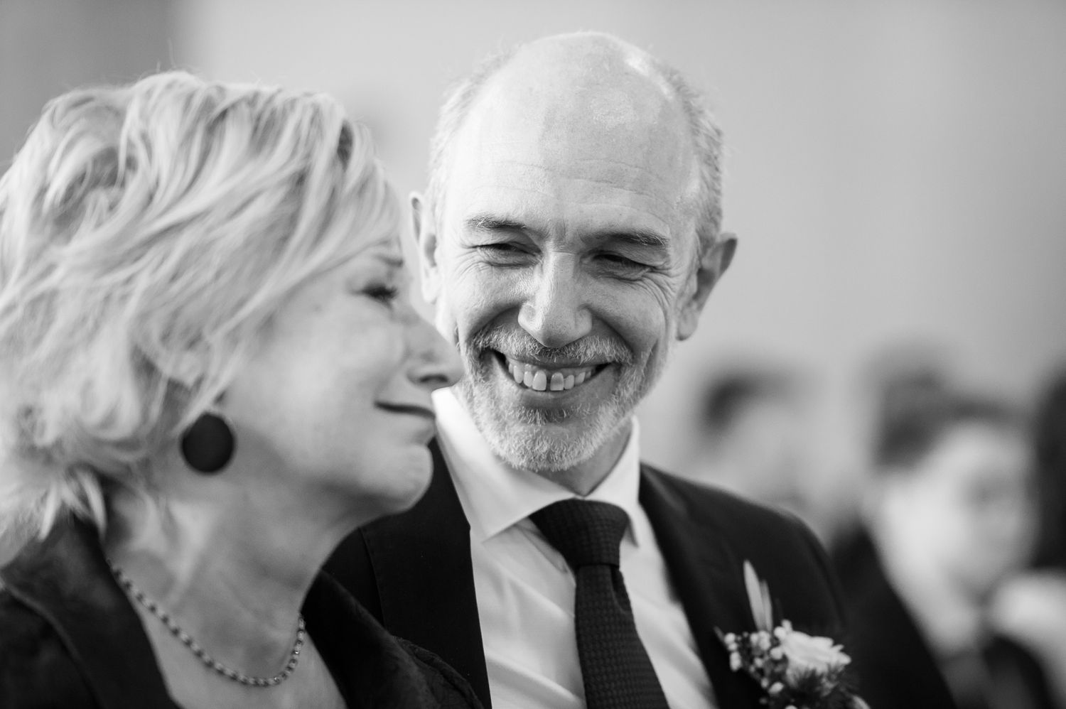 Black and white photo of a smiling couple sharing a joyful moment together at a wedding ceremony.