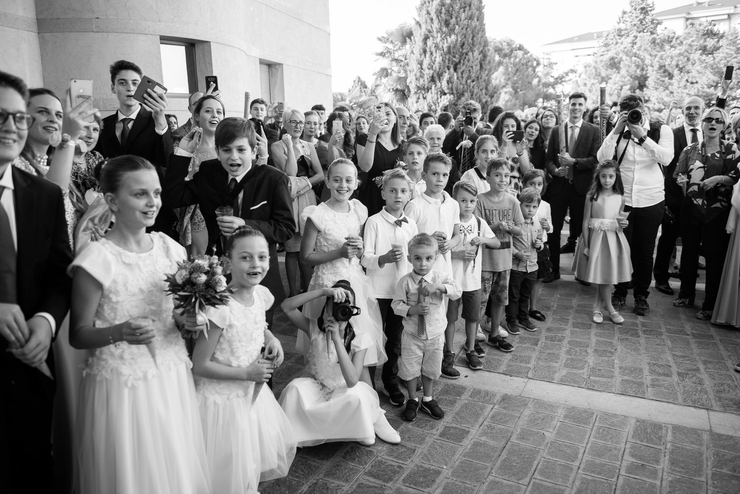 Black and white photo of wedding guests and children gathered outside a church.