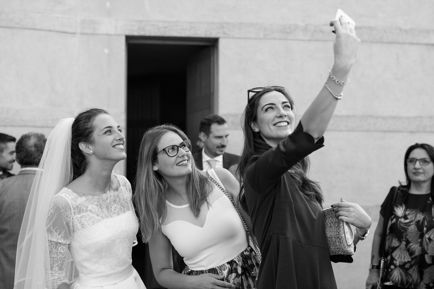 Bride and guests taking selfie outside church after wedding ceremony.