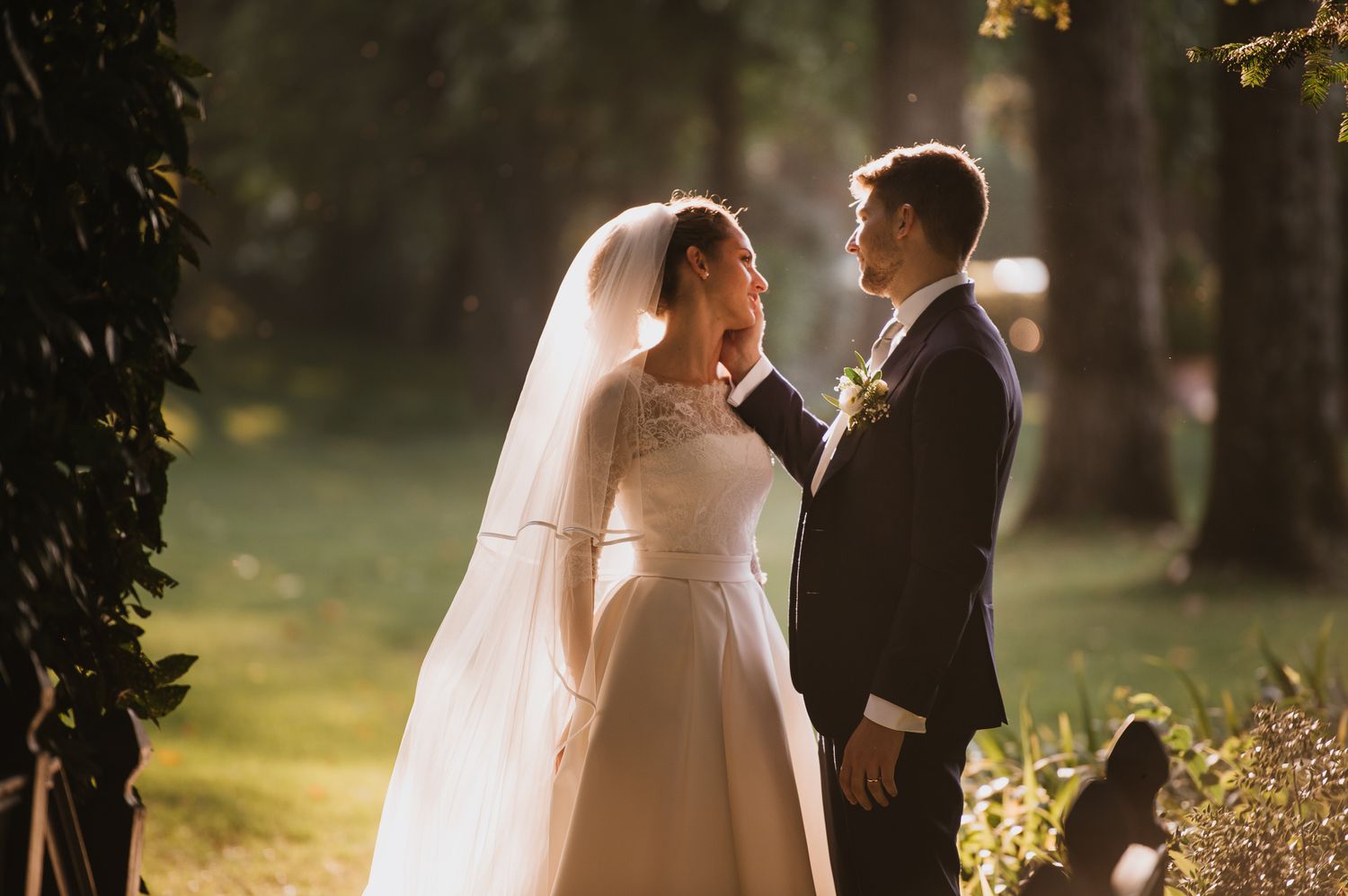 Bride and groom sharing a tender moment in golden sunlight in a garden.