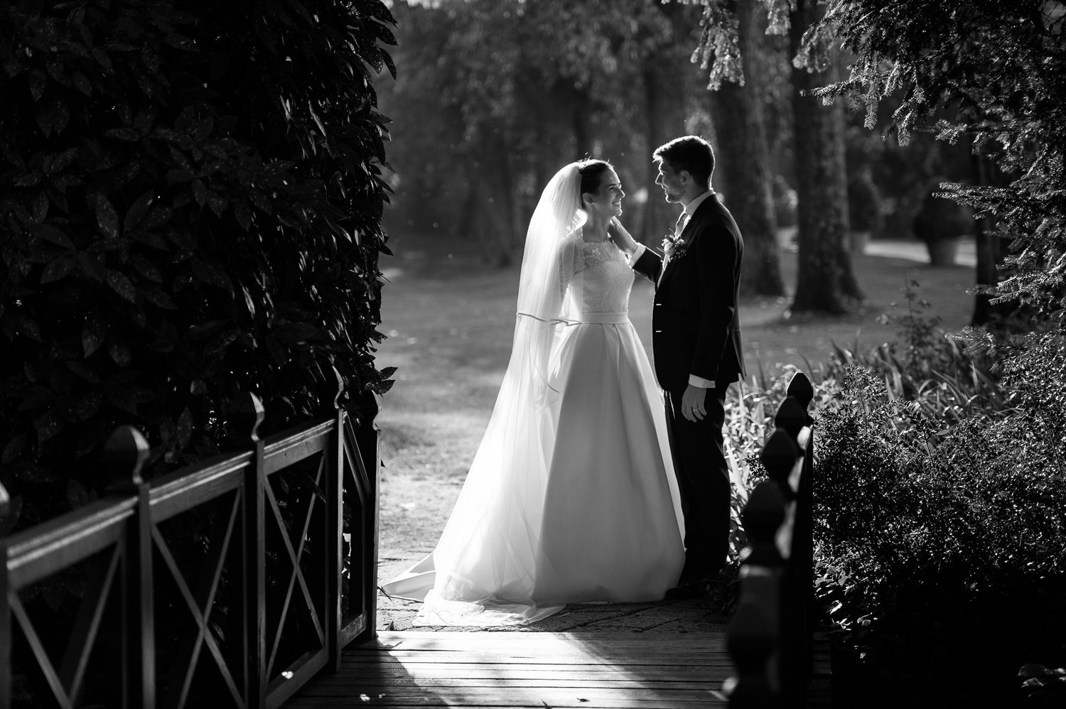 Black and white romantic portrait of bride and groom on a garden path.