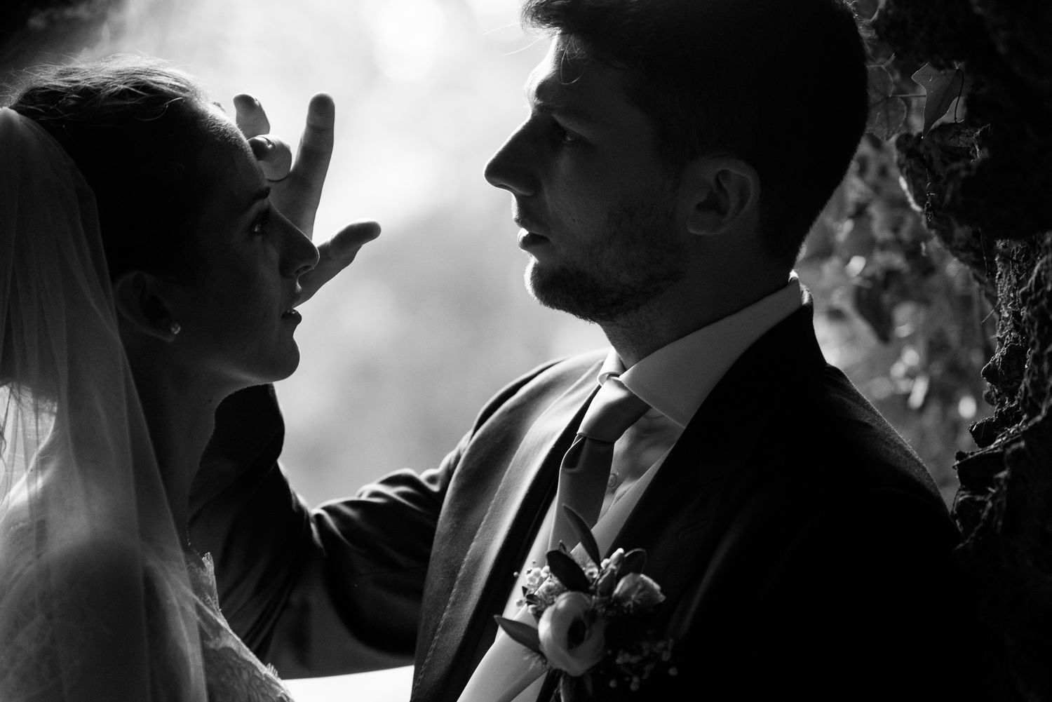 Dramatic black and white close-up of bride touching grooms face at wedding.
