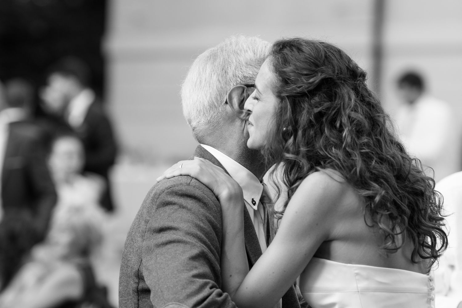 Black and white wedding photo of couple sharing a kiss during ceremony.