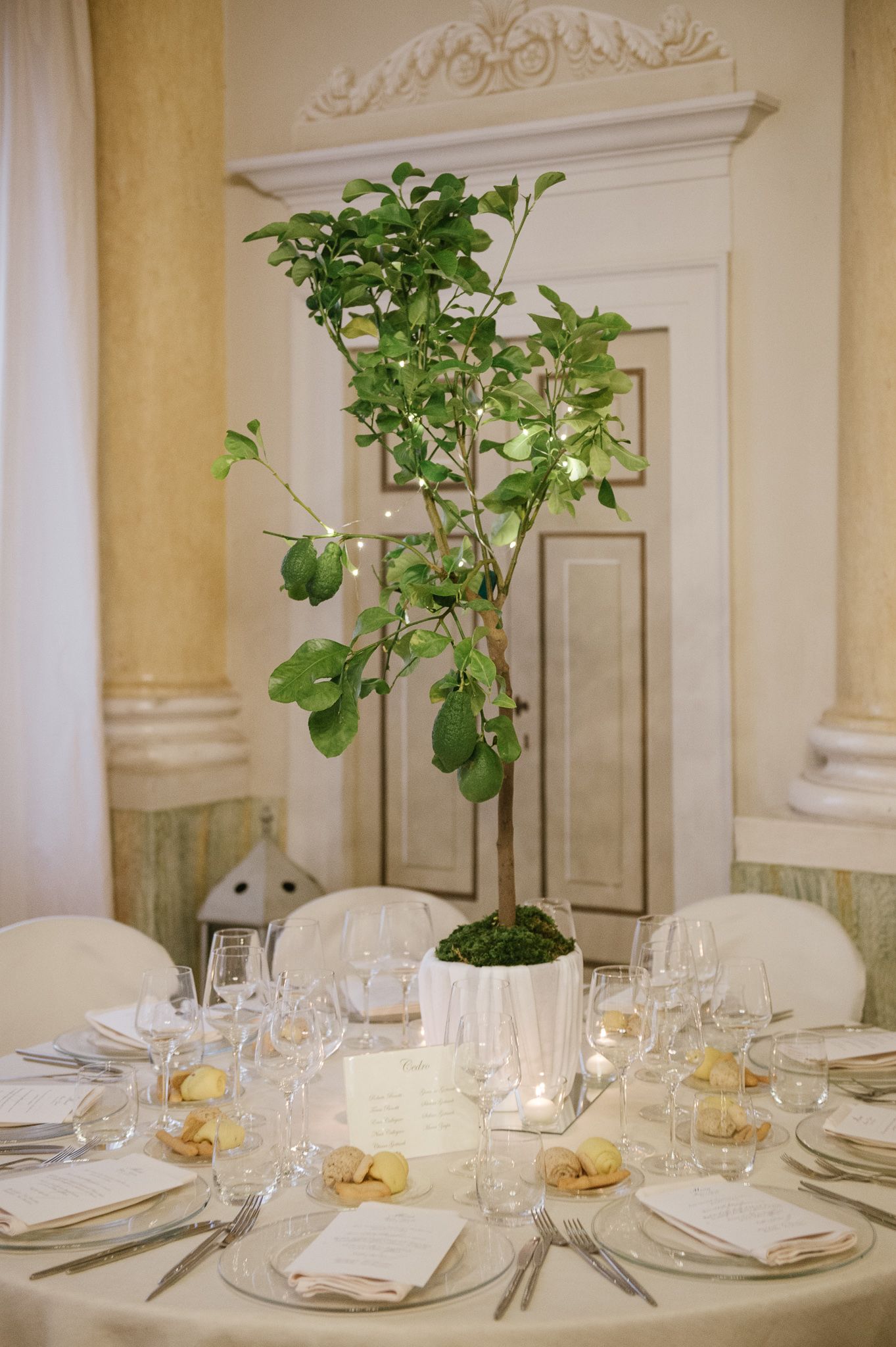 Elegant wedding reception table with tall greenery centerpiece in a classic Italian villa.