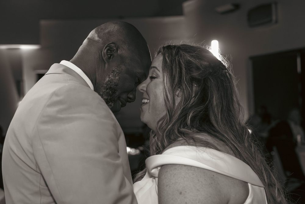 Black and white photo of a joyful couple sharing an intimate moment during their first wedding dance.
