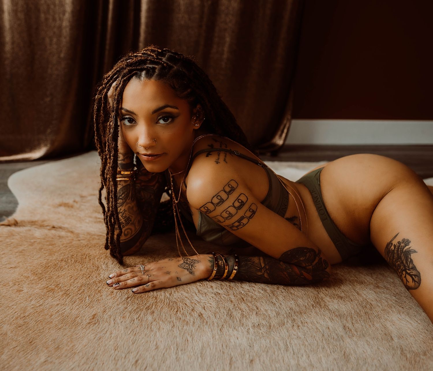 person with tattoos lies on rug in green underwear by KJ Boudoir Photographer