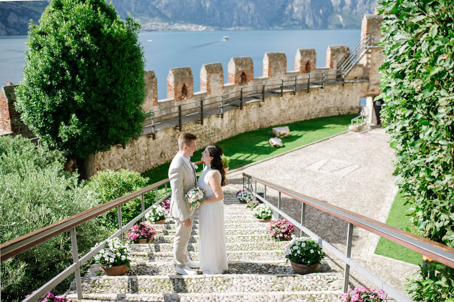 Couple sharing a romantic moment on castle steps with Lake Garda views at a Malcesine wedding.