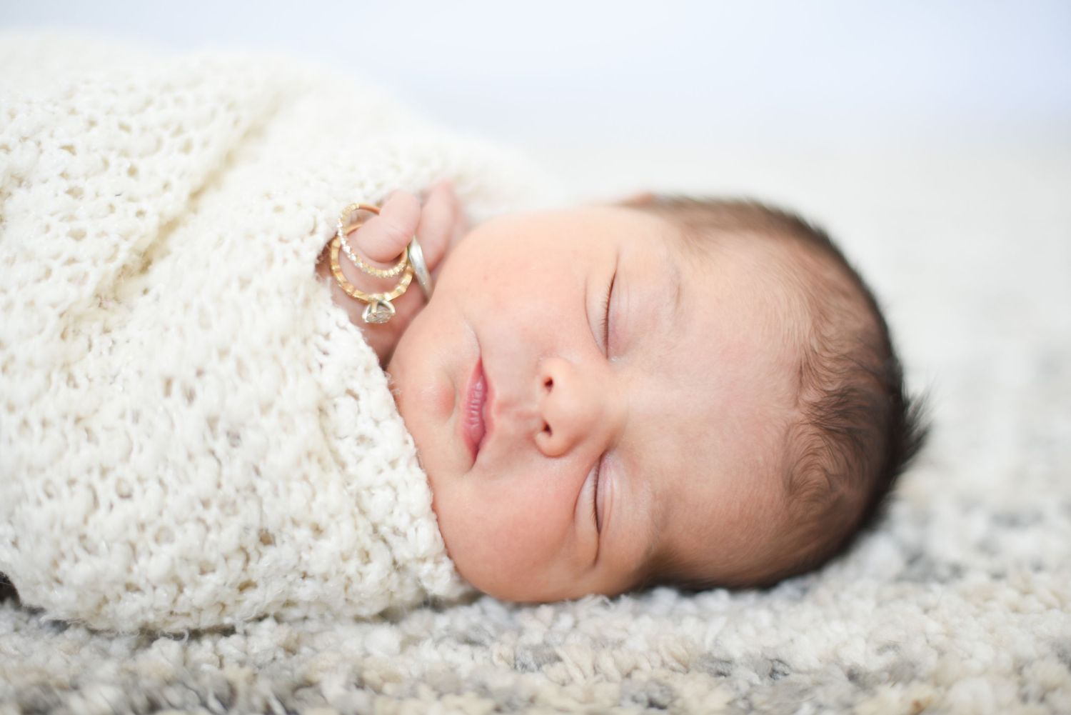 Peaceful newborn baby sleeping on soft white blanket during professional photo session.