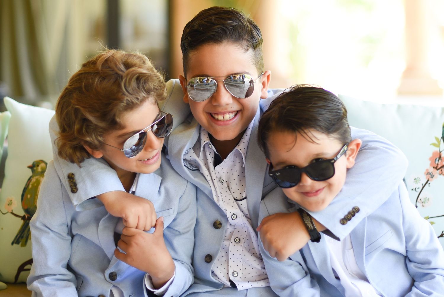 Group wearing matching gray outfits and sunglasses posing together on couch.