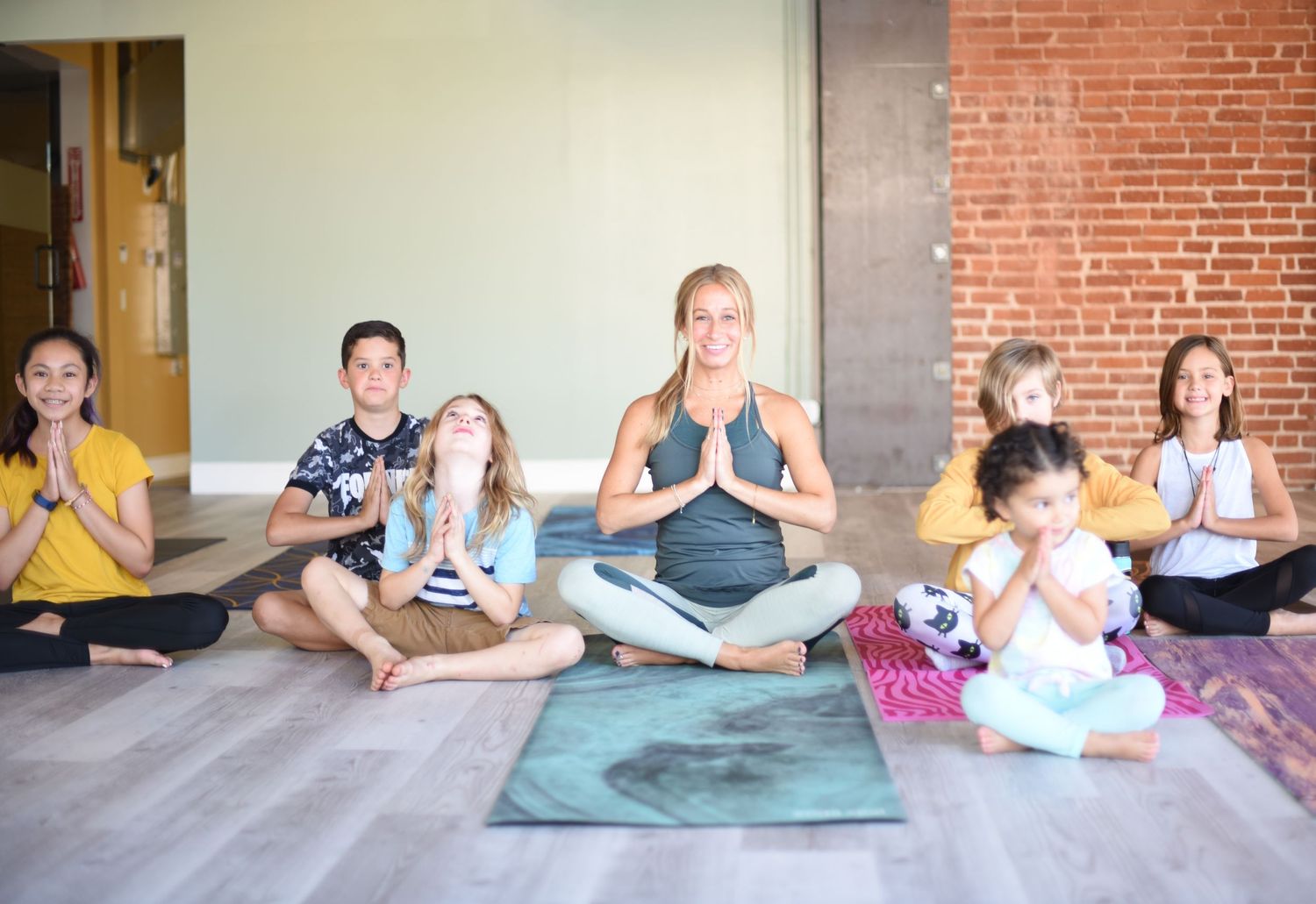 Group practicing meditation and yoga poses together in a studio with brick walls.