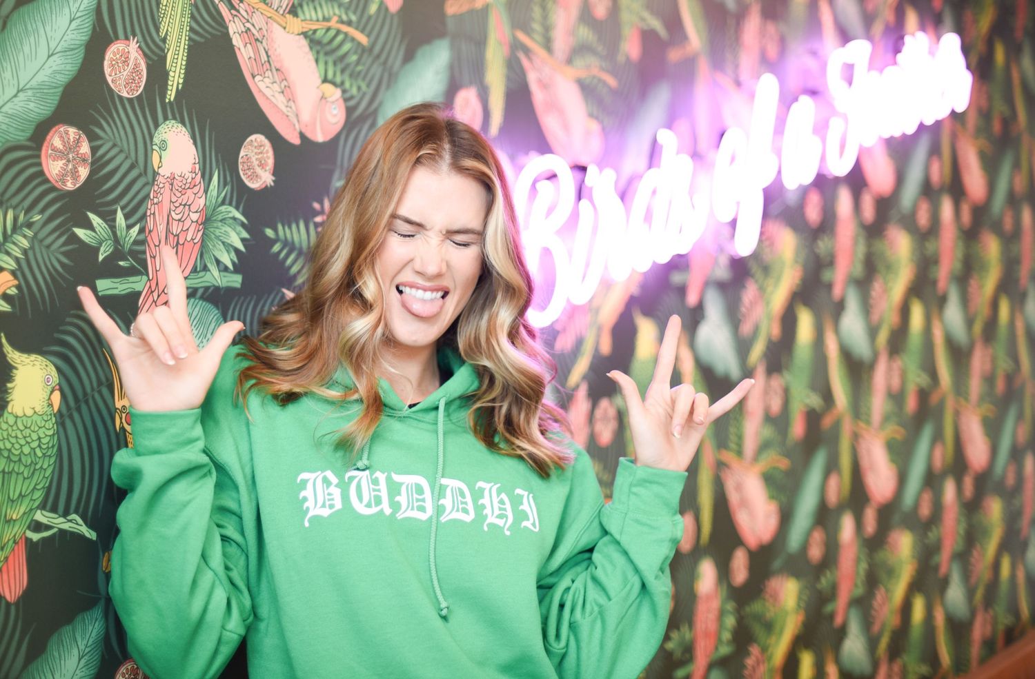 People in green sweatshirts having fun against colorful neon wall backdrop.