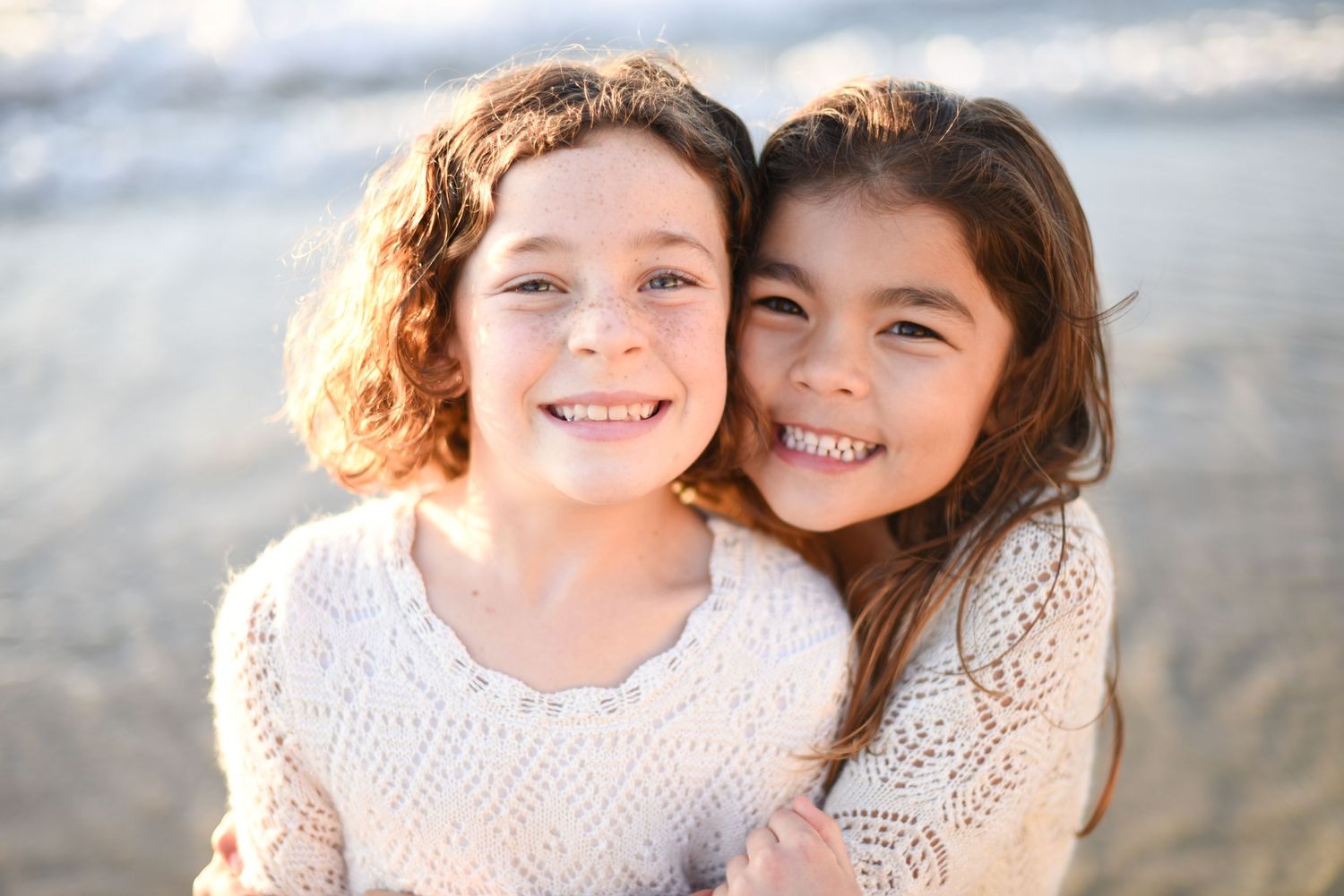 Two young friends sharing joyful moment together on beach.