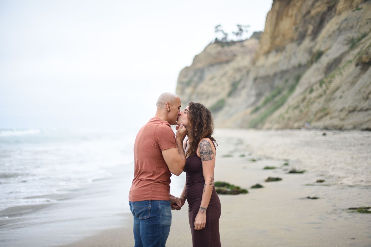 A couple sharing a romantic moment on a scenic coastal cliff path.