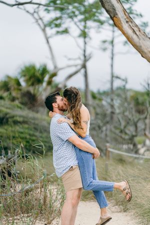 Happy newly engaged couple on near Villas by the Sea beach during surprise engagement planned by on Driftwood Beach