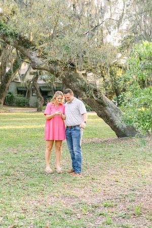 Joyful engaged couple admires the engagement ring on St. Simons Island surrounded by Oak Trees during their proposal photography session