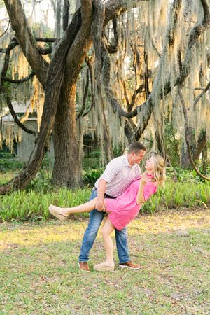 Newly engaged couple dipping and kissing on St. Simons Island surrounded by Oak Trees during their proposal photography session