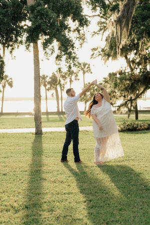 Couple dancing by the Crane Cottage of Jekyll Island behind them, during an engagement photography session portraits in Golden Isles, GA