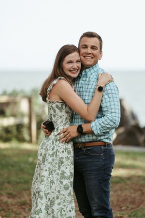 Couple embracing with joy after proposal engagement surprise planned on St. Simons Island near the lighthouse on SSI, Georgia