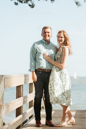 Newly engaged couple casually posed after surprise proposal at beach access point on St. Simons Island