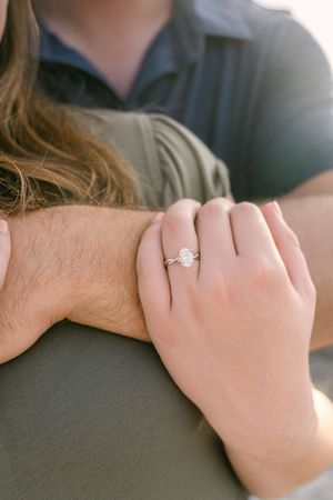 close up of beautiful oval engagement ring during proposal of young couple on beach in south georgia's vacation destination jekyll