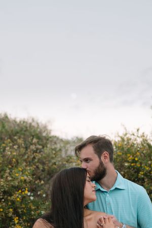 cozy couple leans on one another at sunset portrait session on Jekyll near the beach for engagement photo session