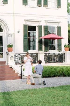 Woman, shocked, wearing white dress, man on one knee proposing, during their engagement on Jekyll Island