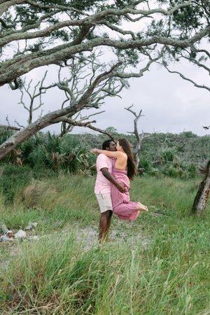Couple embracing under a canopy of driftwood trees near the beach on Jekyll Island during their couples portrait session