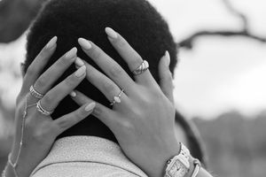 close up of a beach engagement proposal captured at Driftwood Beach on a cloudy day, woman's hand on man, marquee engagement diamond ring