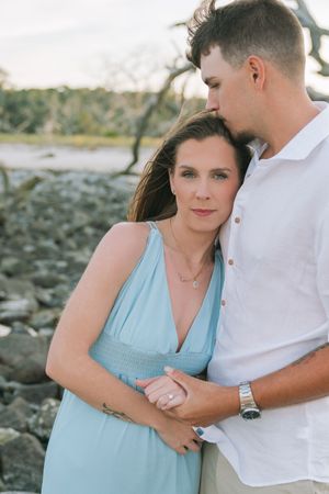 beautiful couple on driftwood beach at sunset during engagement session couples portrait photos with rocks behind them