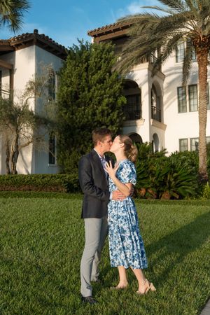 Surprise engagement couple shows ring in front of Sea Island Resort near the beach at sunset by the marsh