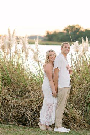 Couple cuddles in tall pom grass along the marshside on St. Simons Island during engagement photo session