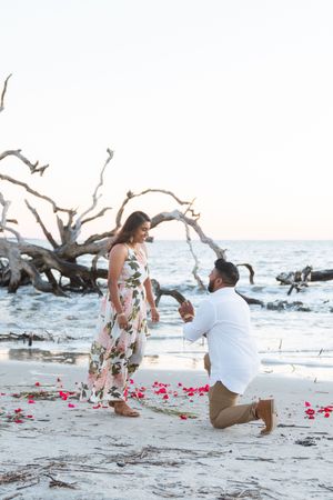 Sunrise proposal in the fall on Jekyll Island Georgia with planned engagement portraits and rose petals on the beach