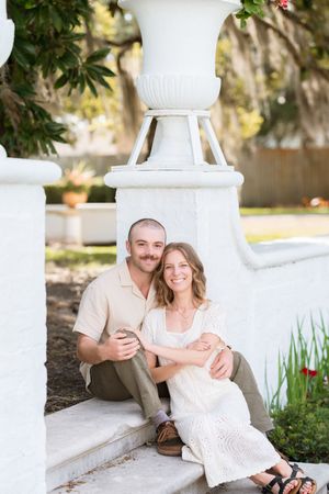 couple smiling with crane behind them during beautiful engagement portraits with their dog on jekyll island proposal