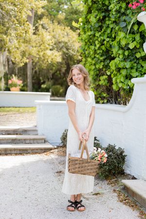 Engagement session photograph captures bride-to-be wearing a white dress, holding a picnic basket, in the historic district of Jekyll Island