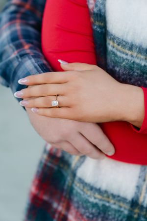 Hands of a couple embracing after a surprise beach engagement and proposal in the Golden Isles at winter time