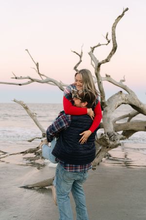 Couple embracing during driftwood beach winter engagement session on Jekyll Island