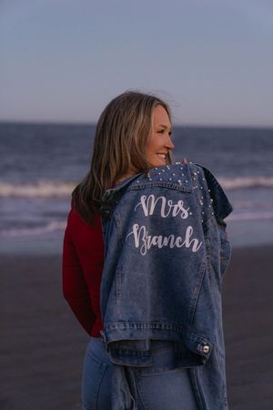 Sunset winter proposal woman wearing a custom jean jacket after getting engaged on the beach of the golden Isles