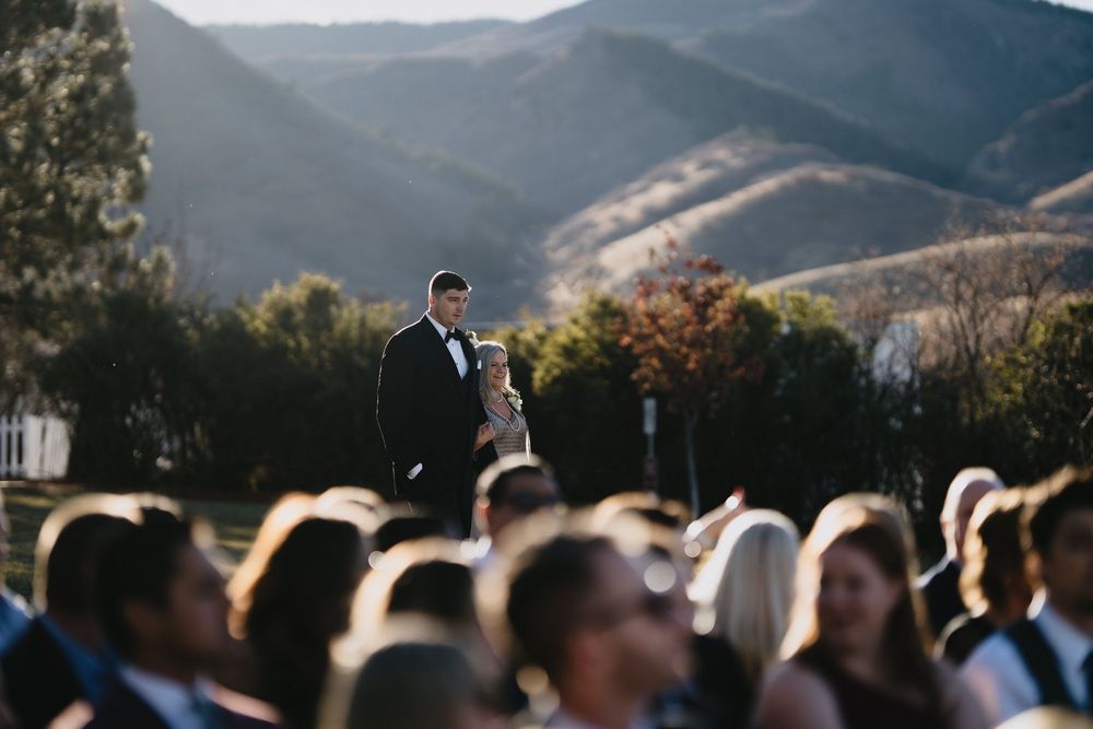 Couple shares a romantic moment during an outdoor wedding ceremony with scenic mountain views in the background.