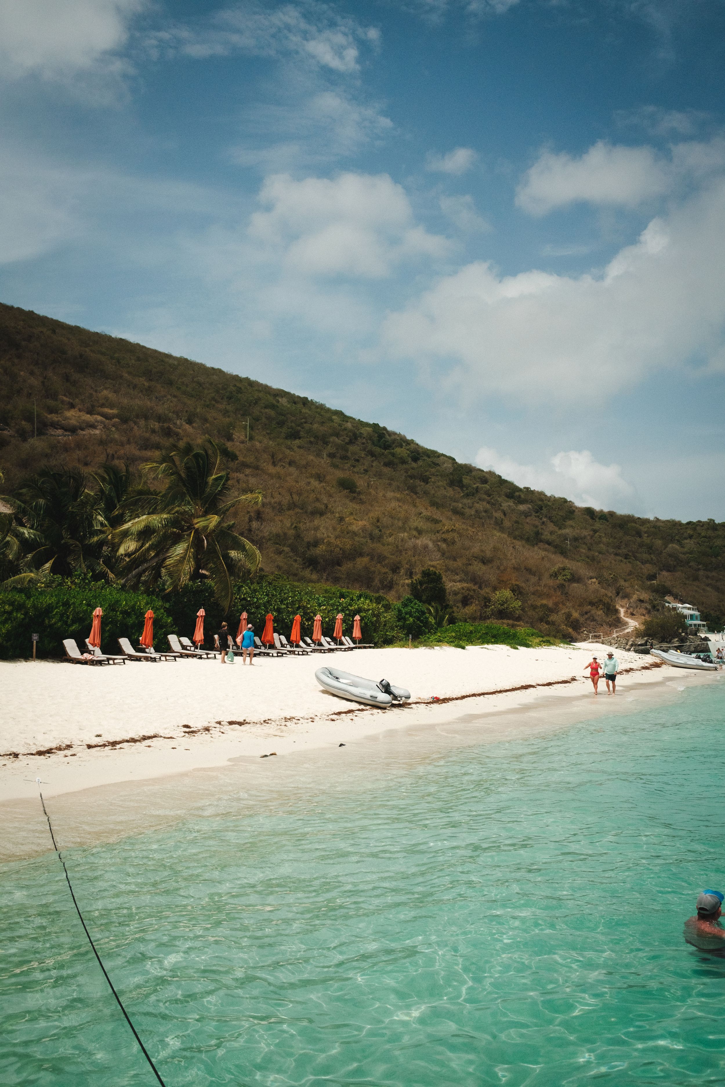 Pristine white sand beach with turquoise water, lounge chairs, and colorful umbrellas on a tropical island.
