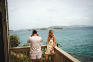 Couple on a wooden balcony overlooking stunning turquoise Caribbean waters on a cloudy day.